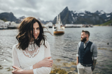 Wedding couple travelers on a hill in Norway, Kvalvika. Beautiful view of the beach, Lofoten, Norway.