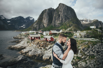 Wedding couple travelers on a hill in Norway, Kvalvika. Beautiful view of the beach, Lofoten, Norway.