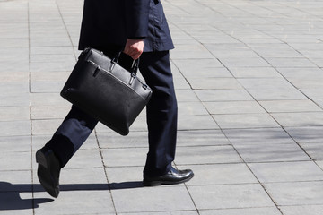 Man with briefcase walking on the street, person in a business suit rushing to a meeting. Concept of businessman, official, politician, career - obrazy, fototapety, plakaty