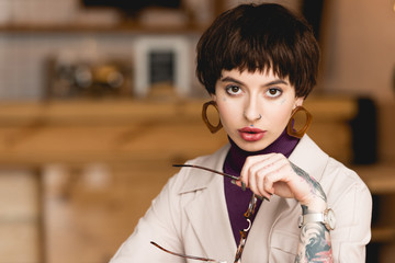 beautiful confident businesswoman holding eyeglasses and looking at camera