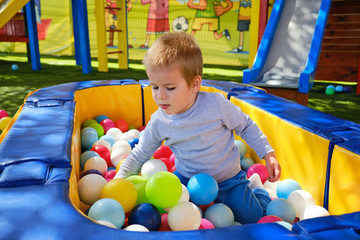 Obraz premium Little boy playing with colorful balls in park playground
