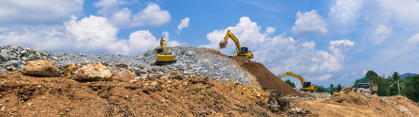 Panorama, Excavators and stone crushing machine of mining under a blue sky with clouds