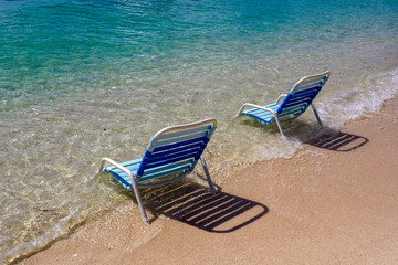 White and blue beach chairs in the sea on the beach on a sunny summer day in tropical island Roatan Honduras