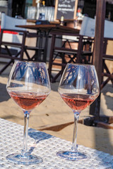 Wine-glasses with chilled rose wine on a sunny summer day on a luxury sandy terrace