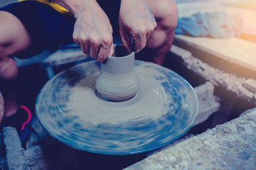 pottery, workshop, ceramics art concept - closeup on male hands sculpt new utensil with a tools and water