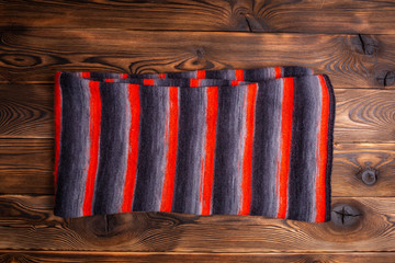 knitted scarf in black and red stripes on a wooden background