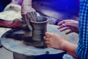 Making it together. close-up to hands of potter teacher and child