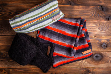 striped knit striped scarves and black knitted sleeves on wooden background