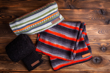 striped knit striped scarves and black knitted sleeves on wooden background