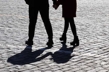 Silhouette of love couple on the street. Two people walking and holding hands, shadows on pavement, concept for romantic love, family, relationships