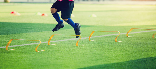 Kid soccer player Jogging and jump cross to between yellow hurdles marker with selective focus