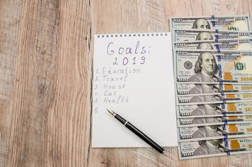 white notebook and pen, calculator and dollars close-up on wooden background