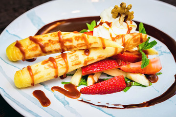 Close up delicious dessert with waffle rolls, ice cream and strawberries