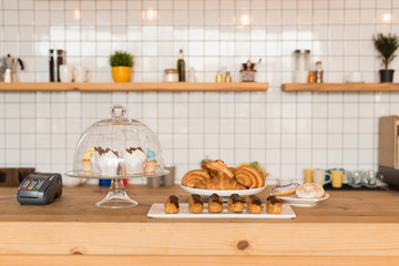 bar counter with cake stand and dishes with delicious desserts and payment terminal