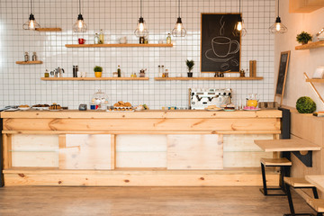 interior of cafeteria with wooden bar counter, shelves and board with drawn coffee cup