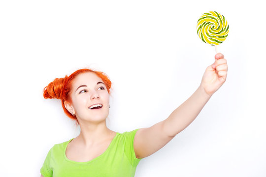 Pretty redhead young girl with lolipops isolated on white