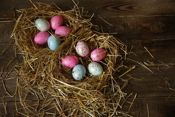 Colorful Easter eggs in a nest of straw on a rustic table. Flat lay. Top view. Easter background.