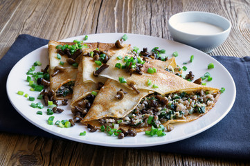 crepes with minced forest mushrooms, pork brisket, and fried onion decorated with green onion, and honey agarics and served with sour cream 