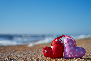 Image of a soft toy in the shape of a heart on the beach.