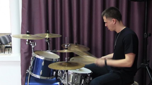The guy plays the drums. Side view