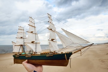 Scale model of a wooden sailing ship on the coast of the Baltic Sea on a cloudy spring day
