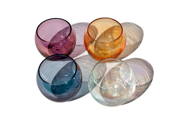 Four multicolored vintage round glasses on a white background with beautiful colored shadows in sunlight isolated close up top view