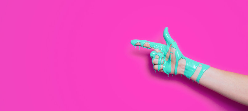 female hand in the paint flowing down the finger shows the direction on a colored background, creative idea of advertising, a gesture of clicking