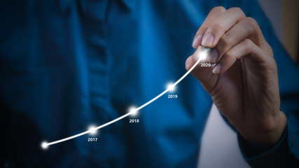 Businessman using pen drawing graphics line year growing graph.