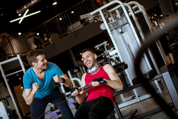Young man with trainer doing exercise in the gym