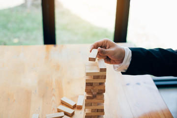 Hand of businessman playing wood blocks stacks game with planning strategy of project management.