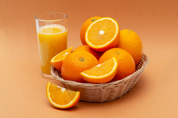 a basket of oranges and a glass of orange juice