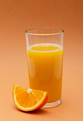 a glass of orange juice on an orange background with a slice of orange