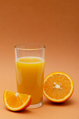 a glass of orange juice on an orange background with a slice of orange