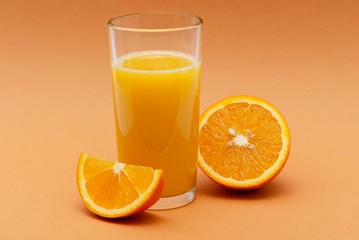 a glass of orange juice on an orange background with a slice of orange