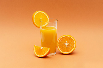 a glass of orange juice on an orange background with a slice of orange