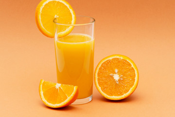 a glass of orange juice on an orange background with a slice of orange