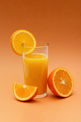 a glass of orange juice on an orange background with a slice of orange