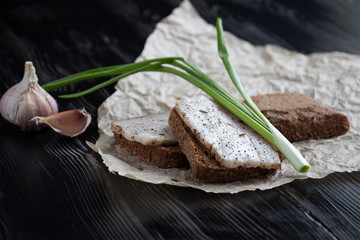 Close-up of black bread with lard, green onions and garlic