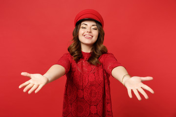Obraz na płótnie Canvas Portrait of smiling charming young woman in lace dress cap standing with outstretched hands isolated on bright red background in studio. People sincere emotions lifestyle concept. Mock up copy space.