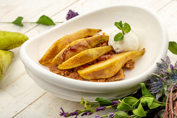 roasted pear in caramel on homemade hazelnut cookies and ice cream ball