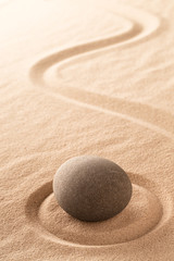 Japanese zen meditation stone garden with round rock in raked sand.