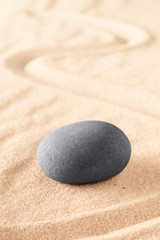 Fototapeta na wymiar round stone on sand with line. Zen meditation or spa wellness background. Japanese sandy garden.