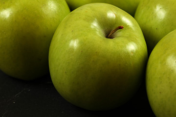 Closeup of green apples on black board, detailed photo - texture on apple skin visible.