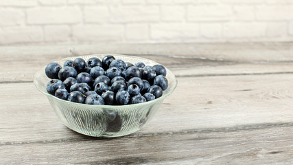 Small glass bowl with blueberries on gray wood desk