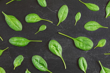 Corn salad ( Valerianella locusta ) leaves arranged in pattern over black slate like board - overhead shot. Healthy green leaf food concept.