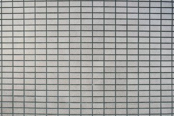 Grey tiles wall texture installation in straight or stack bond. Close-up.