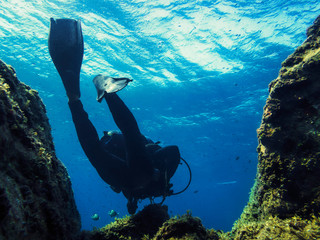 man diving through the blue sea near of the seabed