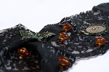 black lace with orange beads, decorative green butterfly, frame and rhinestones on white background with copy space