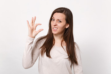 Portrait of puzzled young woman in light clothes gesturing demonstrating size with workspace isolated on white wall background in studio. People sincere emotions lifestyle concept. Mock up copy space.
