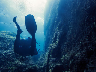 silhouette of a diver going through a rocky canyon